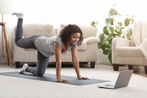 A person smiles at her laptop while doing Pilates at home. Modifying Pilates moves to suit your body...