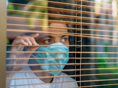 Coronavirus. Sick man of corona virus looking through the window and wearing mask protection and rec...