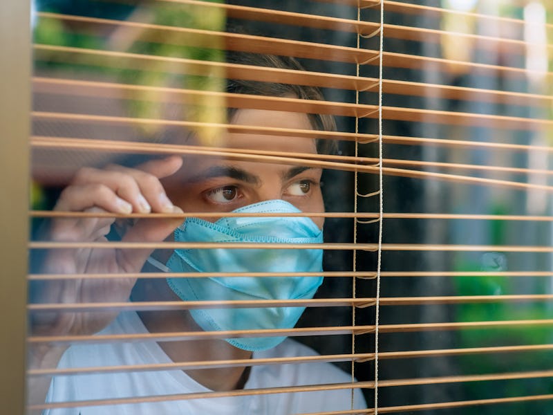 Coronavirus. Sick man of corona virus looking through the window and wearing mask protection and rec...