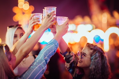 Female friends cheering with beer at music festival