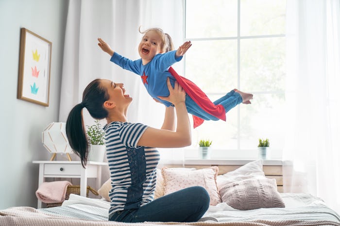 Mother and her child playing together. Girl and mom in Superhero costume. Mum and kid having fun, sm...