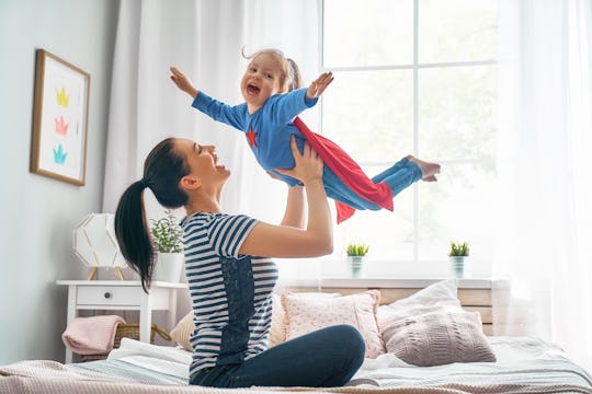 Mother and her child playing together. Girl and mom in Superhero costume. Mum and kid having fun, sm...