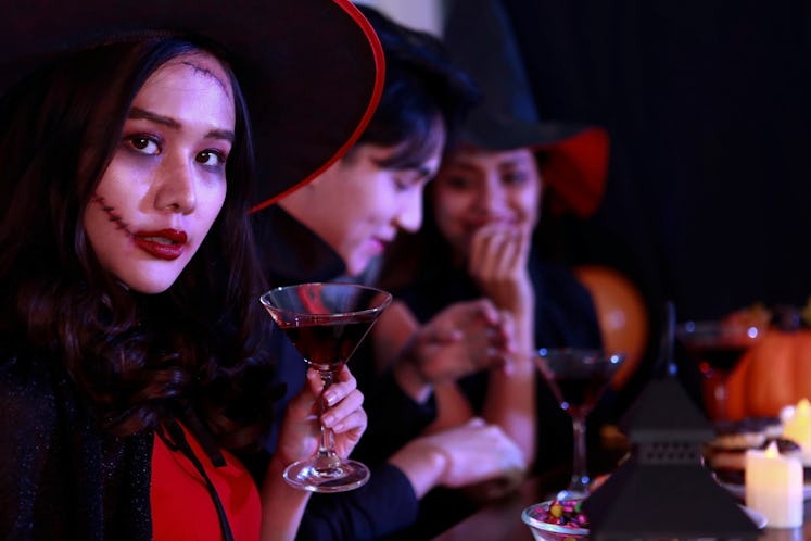 Young Asian drinking in costume celebrating Halloween. Celebration of group young people happy frien...