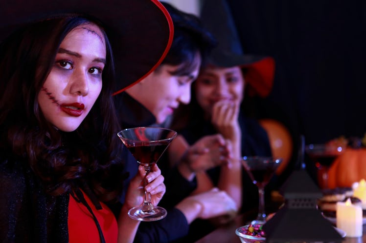 Young Asian drinking in costume celebrating Halloween. Celebration of group young people happy frien...