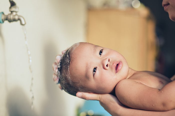 Asian baby son lay on his mother's hands and washing his hair. Add grain for vintage tone.