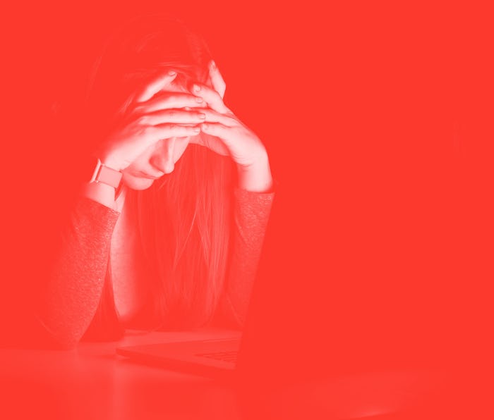 Very tired and exhausted woman, holds her head with hands sitting at the laptop late in the night. ...