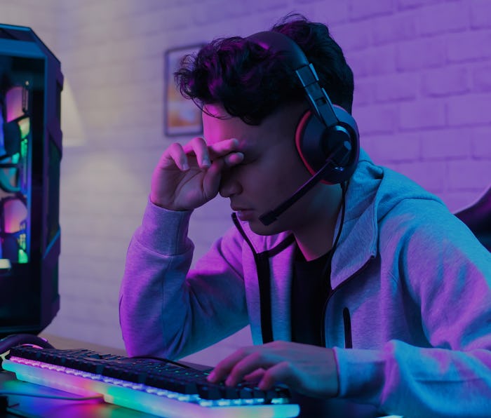 Young asian esport gamer feel painful while playing in Online Video Game because his eye is tired