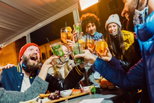 Group of friends drinking at cocktail bar with open face masks - Happy young people having fun toget...