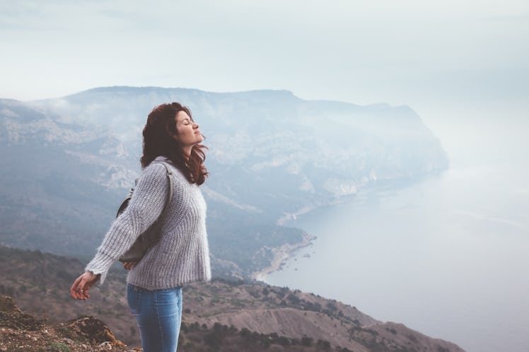 Girl travel in mountains alone. Spring weather, calm scene. Backpacker walking outdoors, back view o...