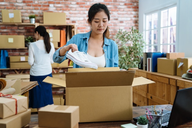 Startup small business entrepreneur SME freelance woman work with box. Young Asian lady worker in office online marketing packaging parcel delivery e commerce concept. girl packing shoes in cardboard