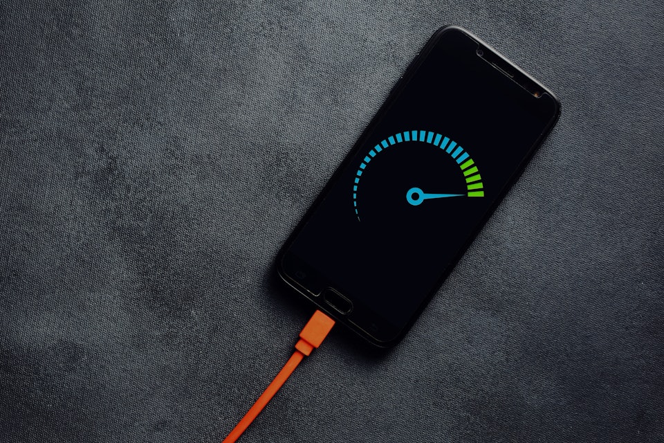 Smartphone connected to a usb charging cable and fast charging on black background. Phone fast and q...