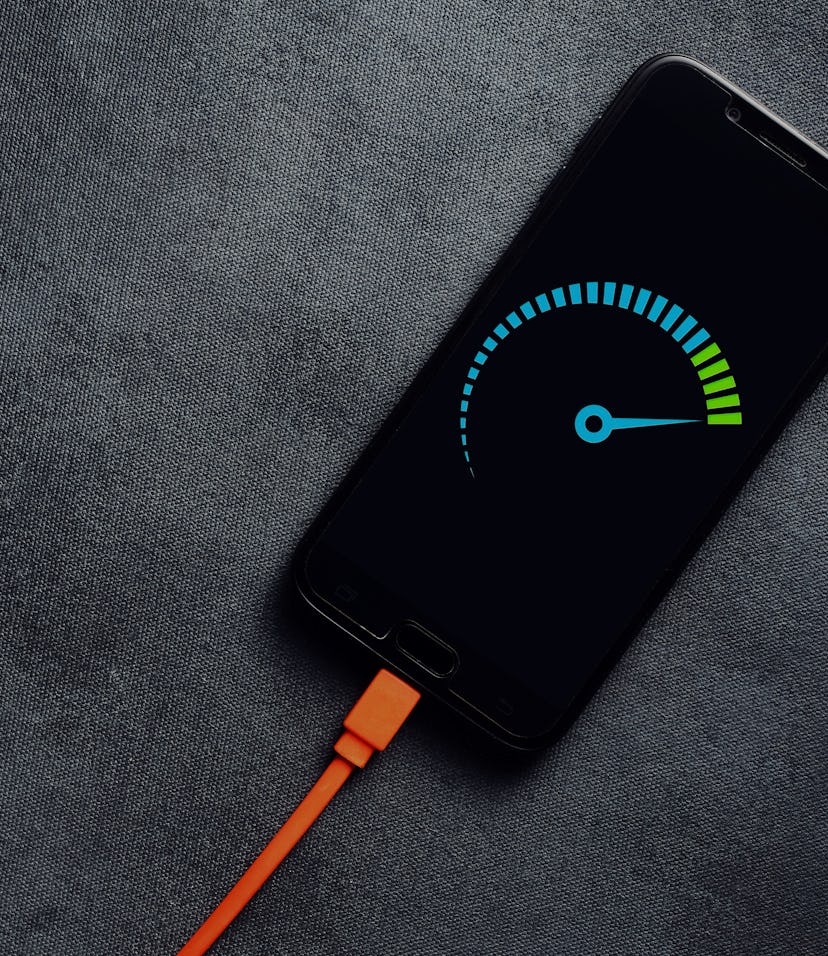 Smartphone connected to a usb charging cable and fast charging on black background. Phone fast and q...