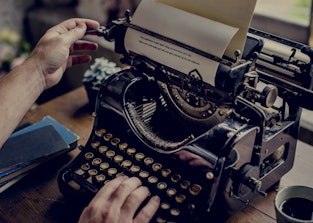 Hands typing on classic vintage typewriter
