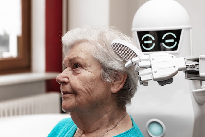 a robotic caregiver is combing the hair of a female senior adult, concepts like household nursing ro...