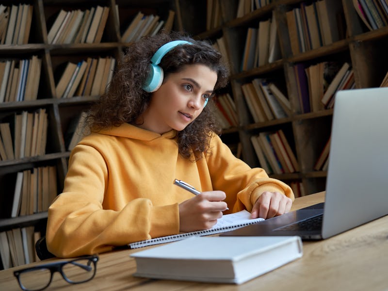 Hispanic teen girl, latin young woman school college student wear headphones learn watching online w...