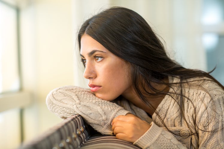 Young woman looking out the window in deep thought.