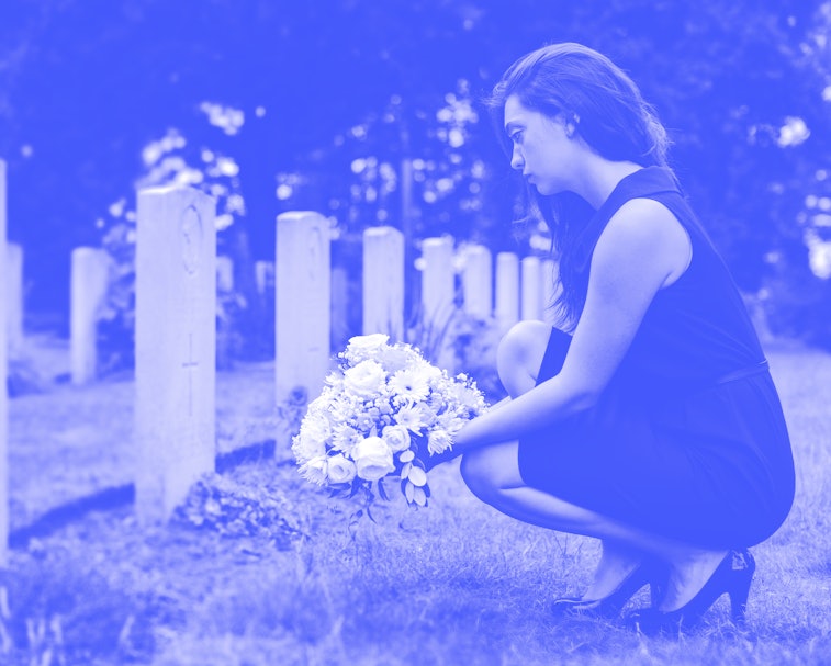 Young widow laying flowers at the grave