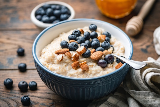Oatmeal porridge with blueberries, almonds in bowl on wooden table background. Healthy breakfast foo...