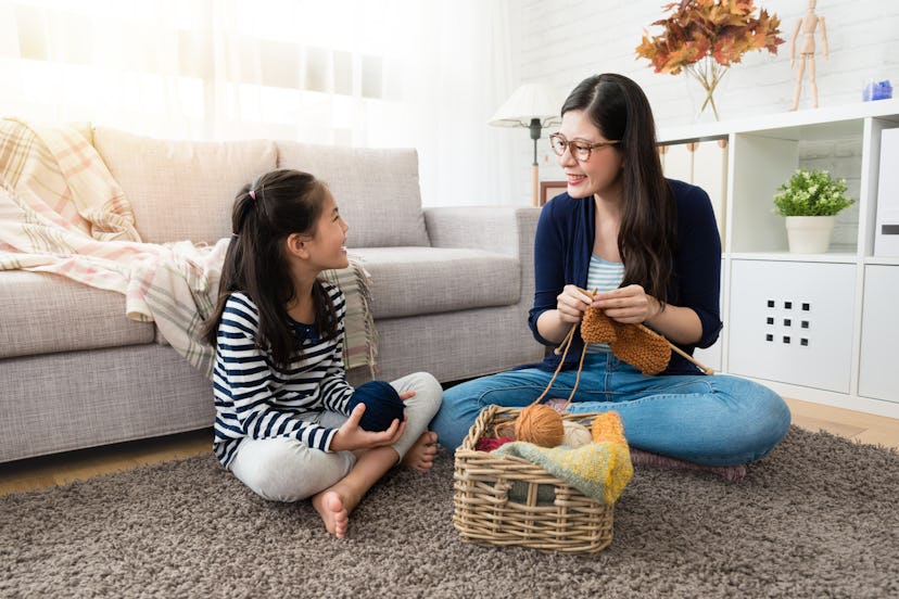 A mom and a daughter knitting together in their living room as an indoor activity
