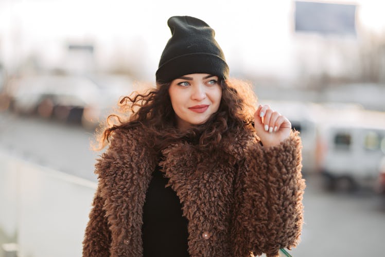 Outdoor portrait of young beautiful fashionable happy smiling girl wearing trendy faux fur winter co...