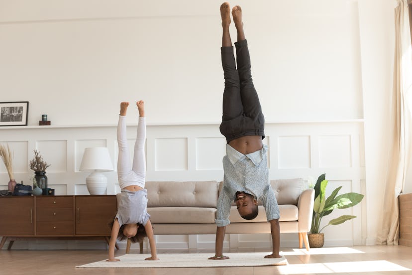A dad and a child both making a handstand in their living room as an indoor activity
