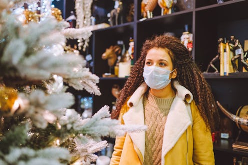 Beautiful afro haired woman wearing protective medical face mask in christmas decorated shop