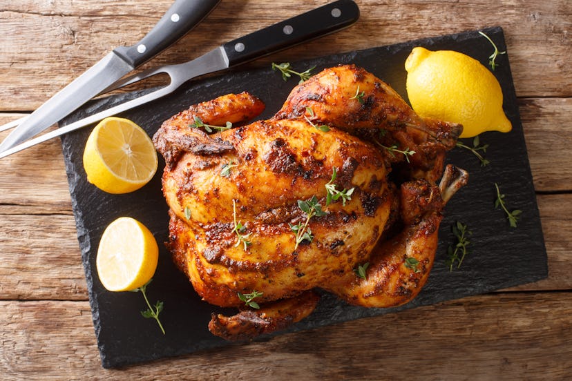 Homemade chicken rotisserie with thyme, lemon closeup on a slate board on the table. Horizontal top ...