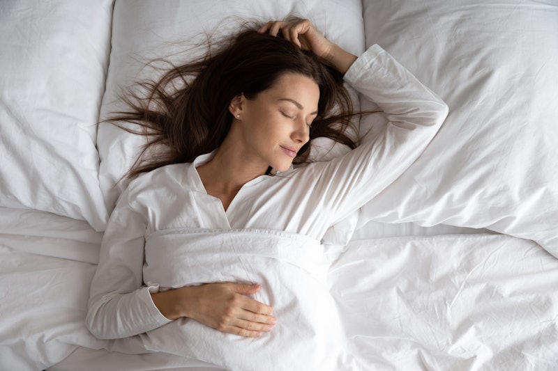Peaceful serene beautiful young lady wear pajamas lying asleep relaxing sleeping in cozy white bed o...