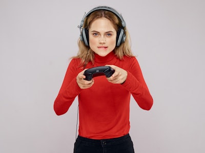 woman in headphones with joystick playing in playstation on gray background                         ...