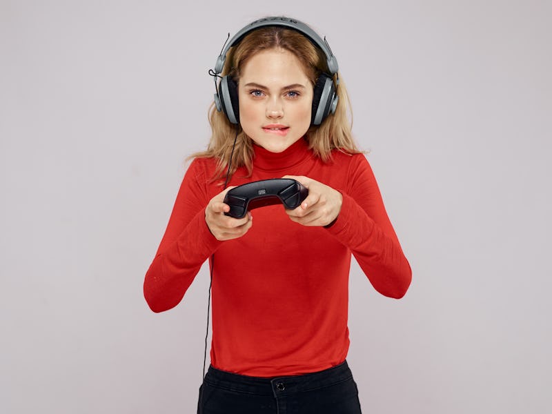 woman in headphones with joystick playing in playstation on gray background ...