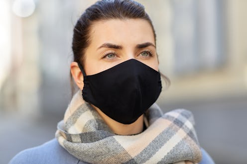 health, safety and pandemic concept - young woman wearing black face protective reusable barrier mas...