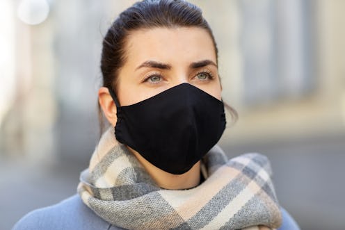 health, safety and pandemic concept - young woman wearing black face protective reusable barrier mas...