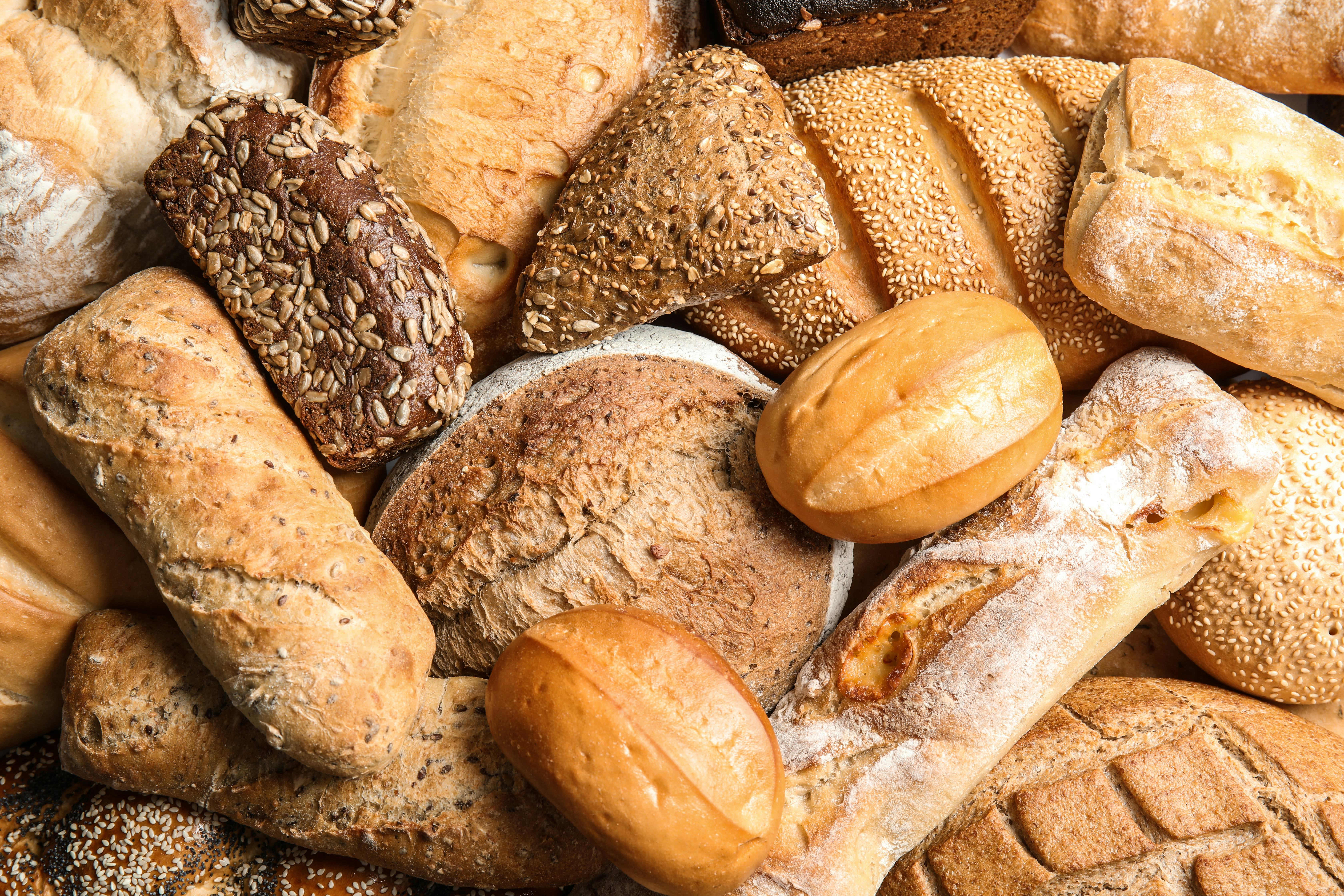 Different kinds of fresh bread as background, top view