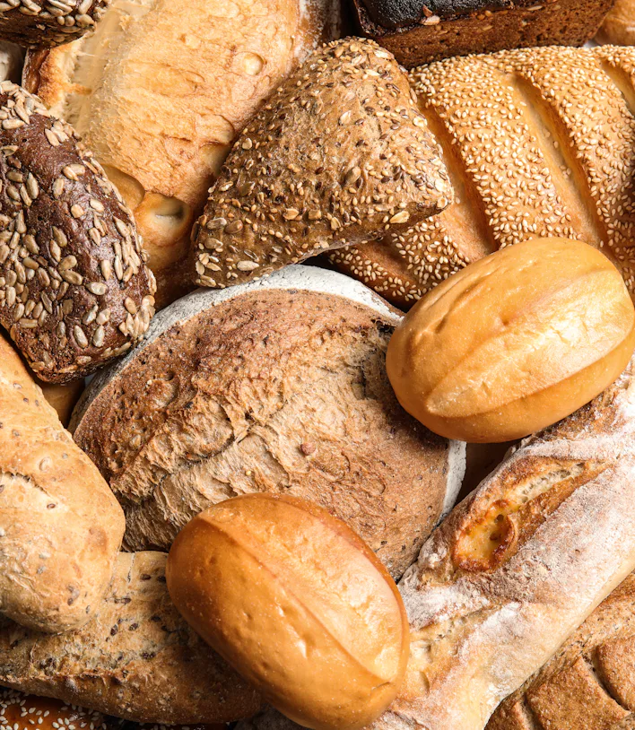 Different kinds of fresh bread as background, top view