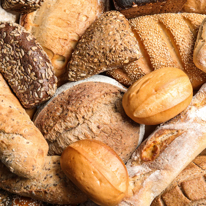 Different kinds of fresh bread as background, top view