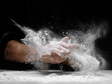 Chef clap white flour dust man hand on black background.