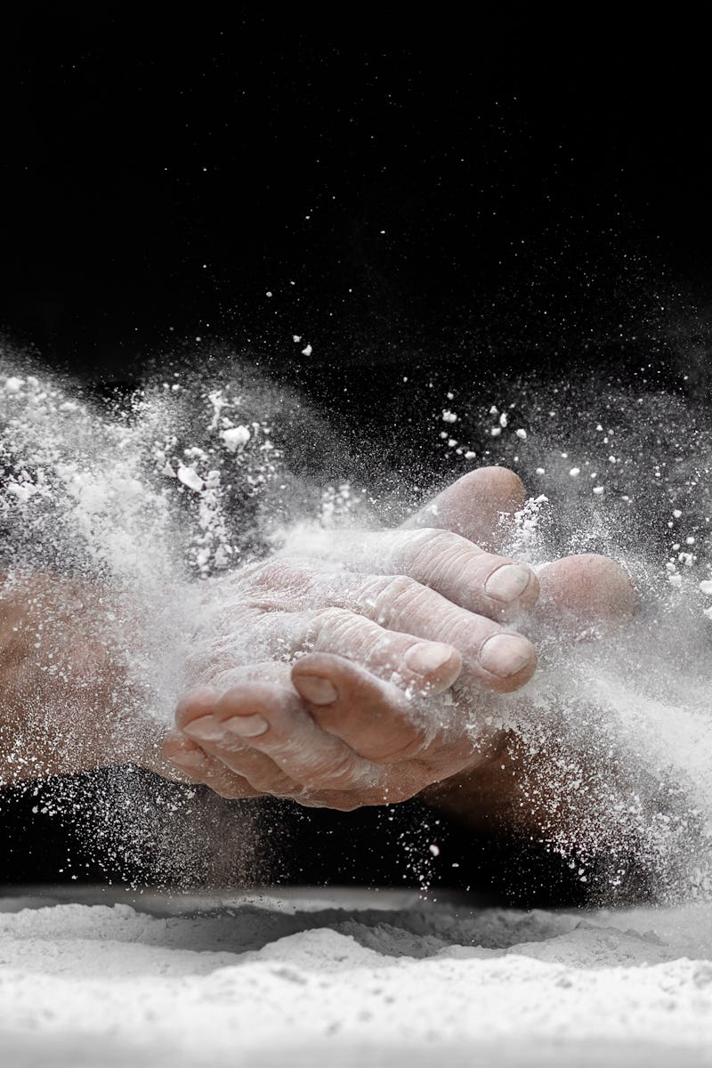 Chef clap white flour dust man hand on black background.