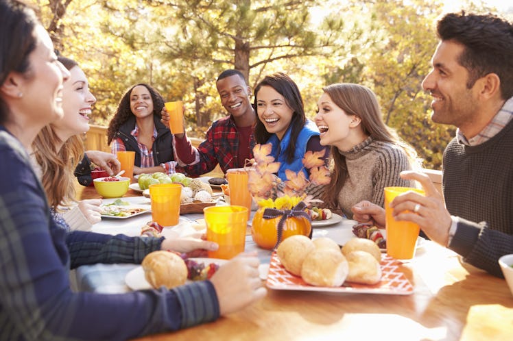 Group of happy friends eat and laugh at a table at a barbecue