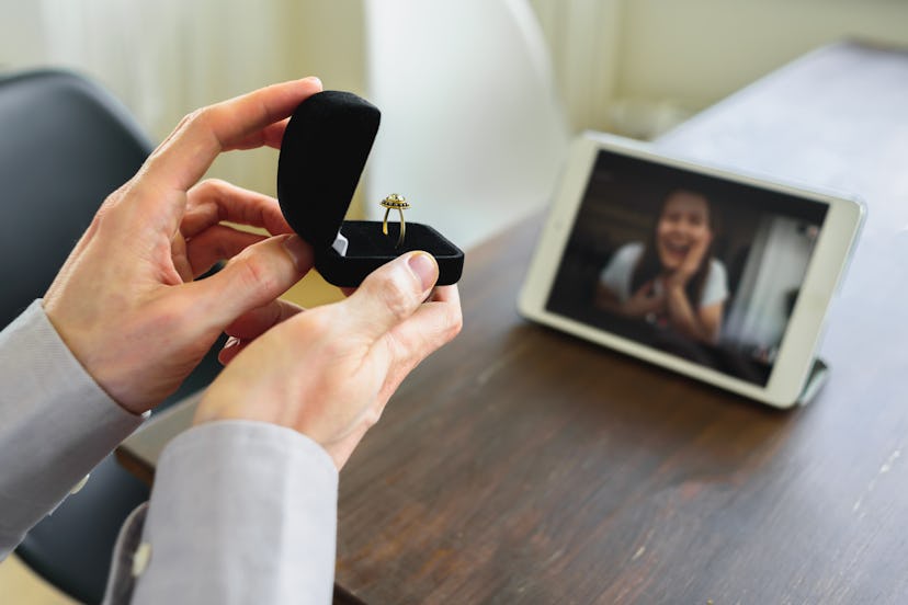 Man making marriage proposal to girlfriend by using online video call. Showing the ring to happy wom...