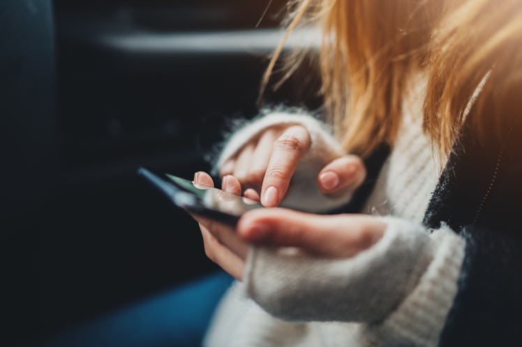 Female hands typing text message social networks on smartphone while traveling by car, woman using d...