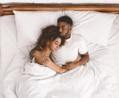 Young african-american couple sleeping together in bed, top view, copy space