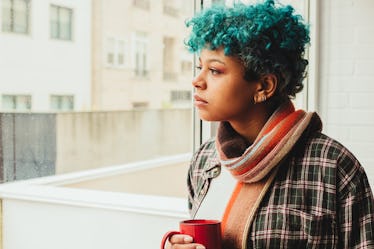 portrait of young girl with blue curl hair at the window with cup and natural light