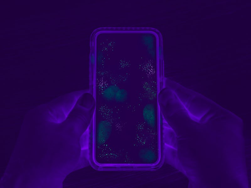 Hands holding cell phone with dirty contaminated touch screen - UV Blacklight exposing infectious ba...