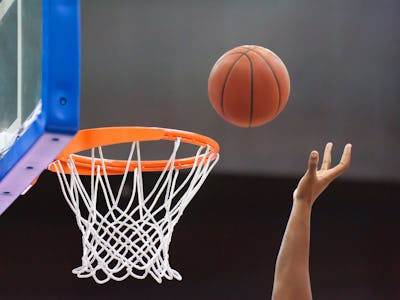 Orange basketball ball flying into the basketball hoop