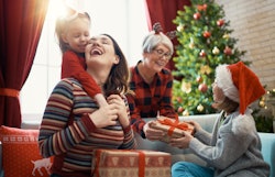 Merry Christmas and Happy Holidays! Cheerful kids presenting gifts to mom and granny. Parents and li...
