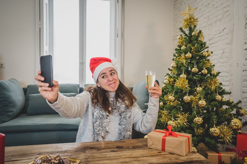 Happy woman in quarantine celebrating virtual christmas video calling family and friend on smart mob...