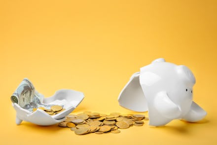Broken piggy bank with money on color background