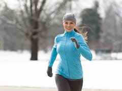 Smiling young woman running jogging in snowy City Park Denver Colorado