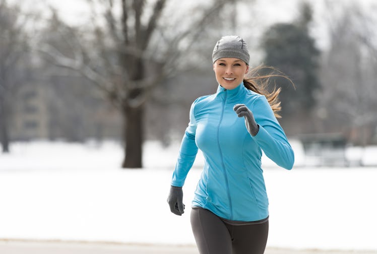Smiling young woman running jogging in snowy City Park Denver Colorado