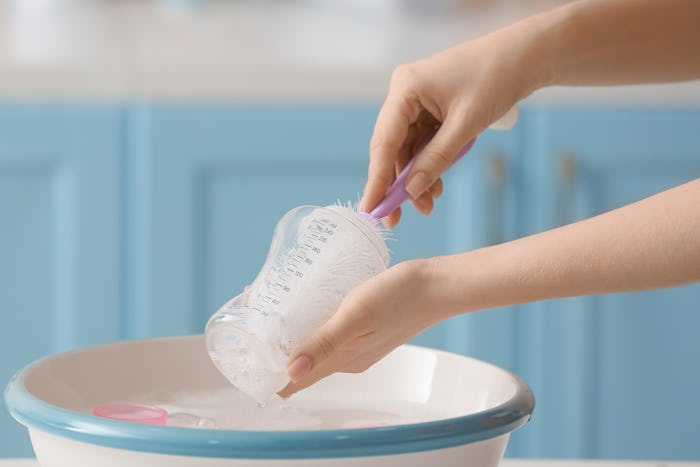 Woman cleaning baby bottle at home